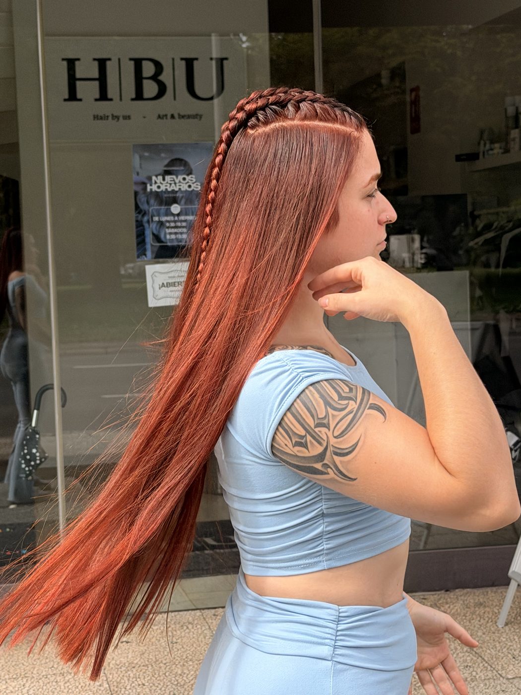Clienta con pelo cobrizo frente a la fachada de HBU Hair Salon